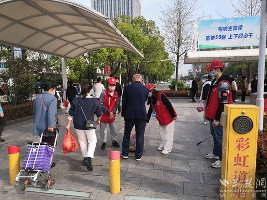 志愿服務(wù)隊(duì)在人民醫(yī)院路口開展文明交通體驗(yàn)活動(dòng)，并幫助老人提重物.jpg.jpg